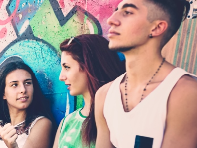 Three teenagers sitting against a wall