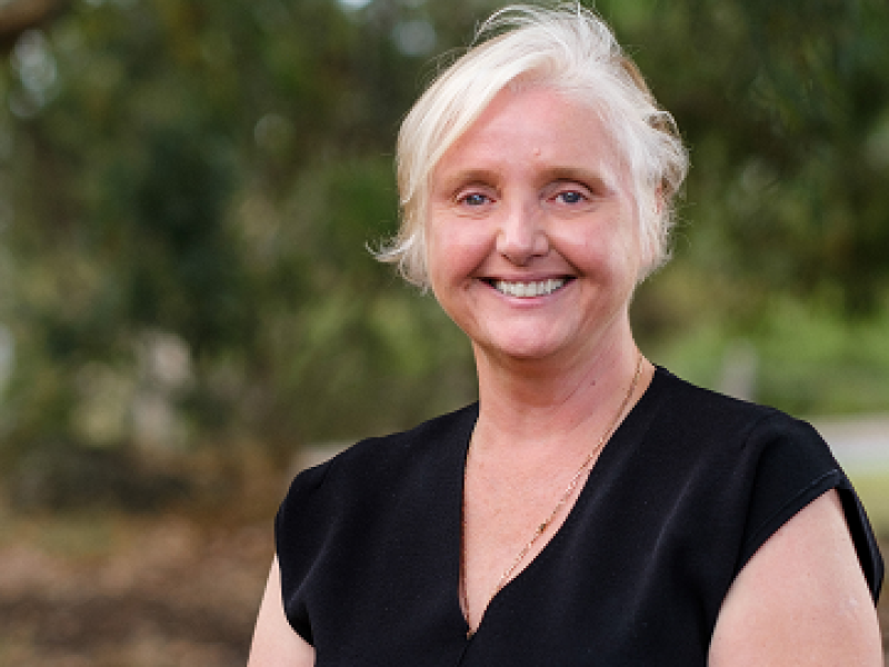 Margaret sitting outside wearing a black dress and smiling