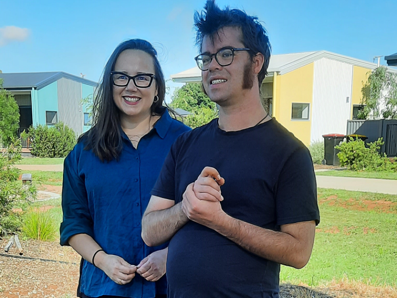 Man and a woman standing outside in front of houses