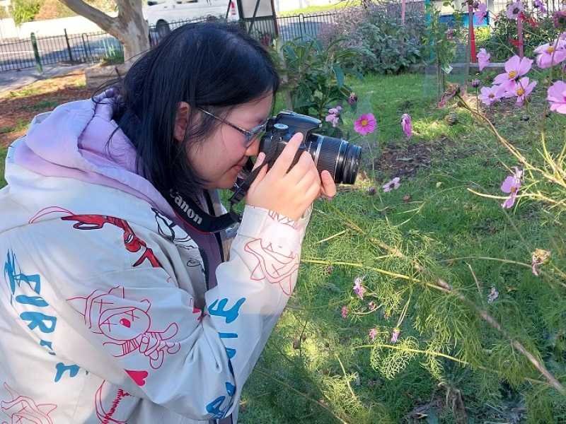 Woman taking a photo of a flower in a garden with a camera