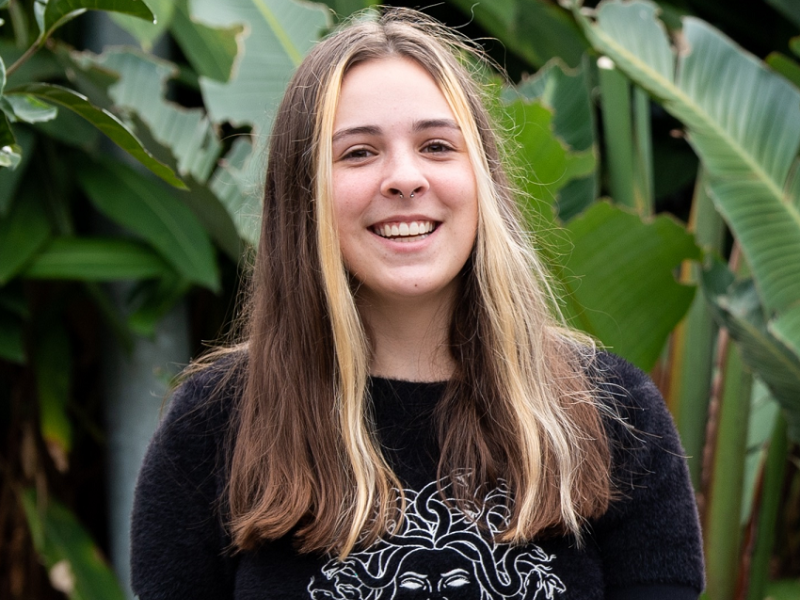 Young woman standing outside in a garden area smiling