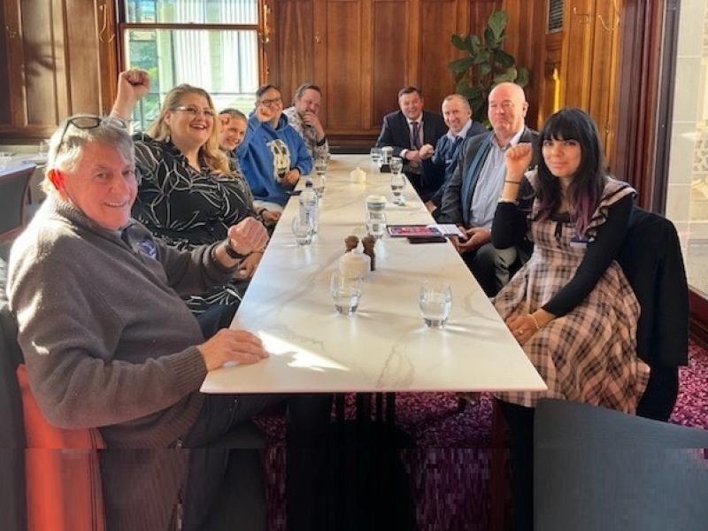 Nine people (both men and women) sitting at a table happy