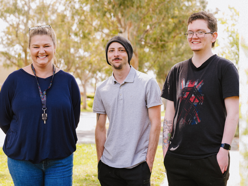 Three people standing outside in front of a tree smiling