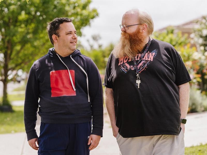 Two men walking outside looking at each other