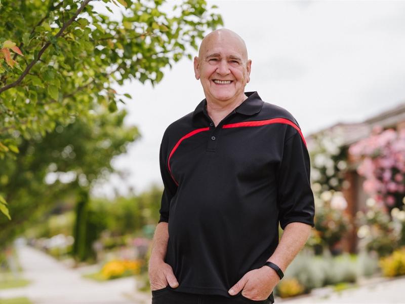 Man outside smiling with both hands in his pants pockets