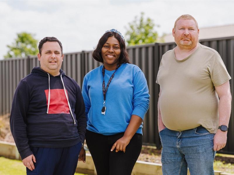 Three people standing outside in a backyard