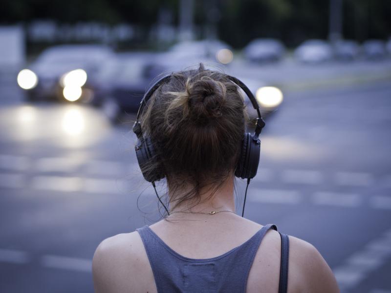 woman with headphones looking out on to a road