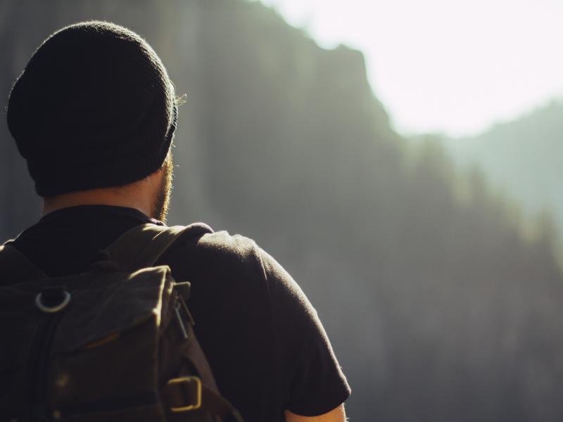 man wearing a backpack looking off into the distance